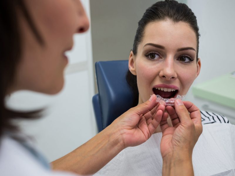 Dentist assisting a patient to wear orthodontic silicone invisible braces